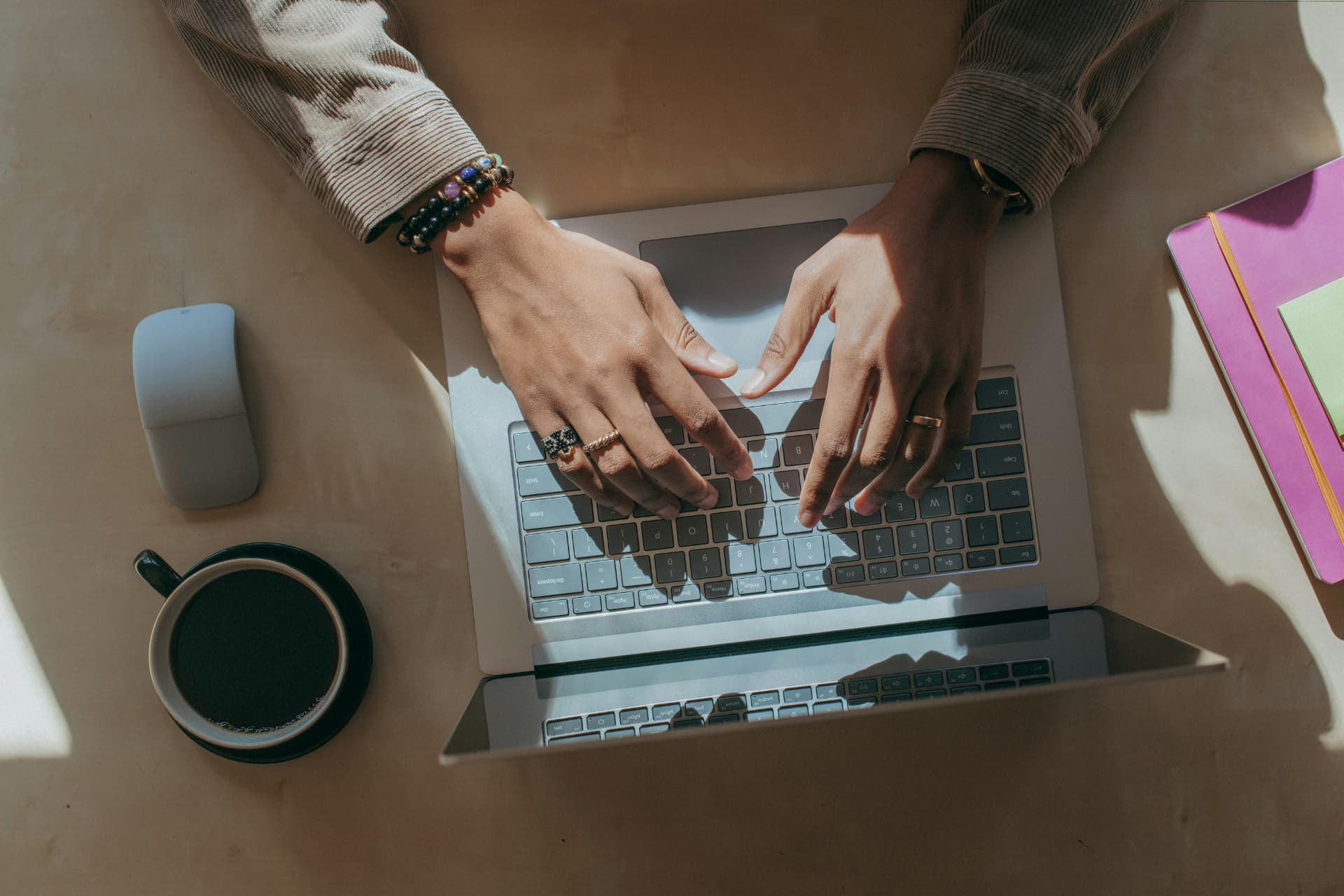 Person som arbetar vid en laptop på ett soligt skrivbord