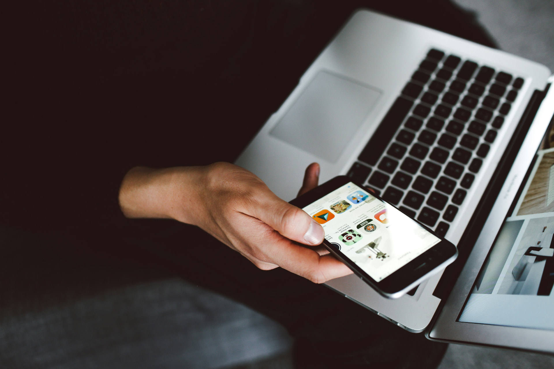 Person som söker i mobilen framför en laptop